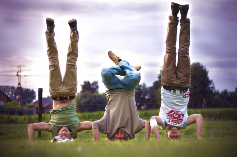 drie jeugdwerkers staan op hun hoofd in een grasveld